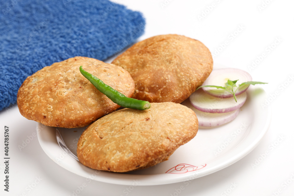 Kachori, green chilly and onion slice in plate. kachori is a spicy snack from India also spelled as kachauri and kachodi. Favorite Tea time snacks Kachori, green chilly and onion slice in plate. kachori is a spicy snack from India also spelled as kachauri and kachodi. Favorite Tea time snacks