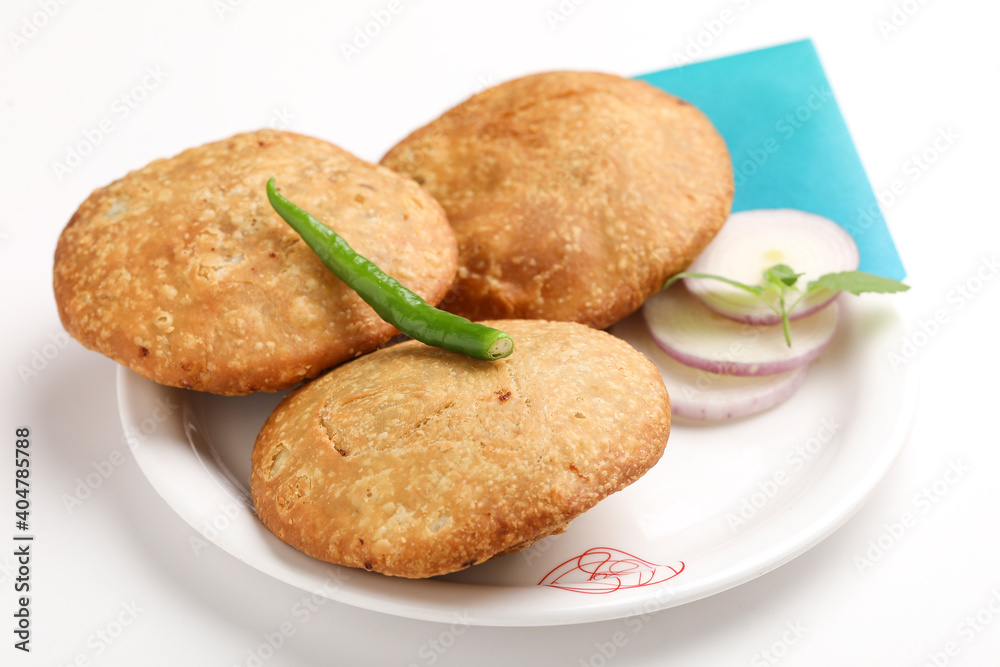 Kachori, green chilly and onion slice in plate. kachori is a spicy snack from India also spelled as kachauri and kachodi. Favorite Tea time snacks Kachori, green chilly and onion slice in plate. kachori is a spicy snack from India also spelled as kachauri and kachodi. Favorite Tea time snacks