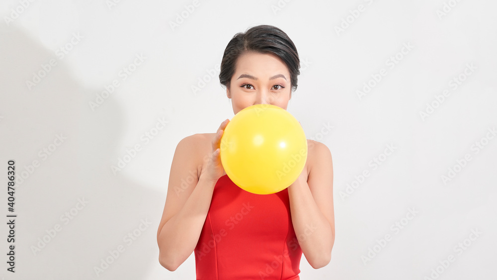 Fashion Beauty Girl blowing a yellow balloon. Gorgeous Woman Portrait. Stylish Haircut and Makeup Fashion Beauty Girl blowing a yellow balloon. Gorgeous Woman Portrait. Stylish Haircut and Makeup