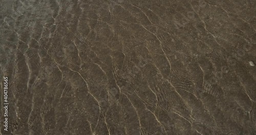 Clear water with small ripples with glare from the sun, clean, shallow bottom, a fragment of a fountain