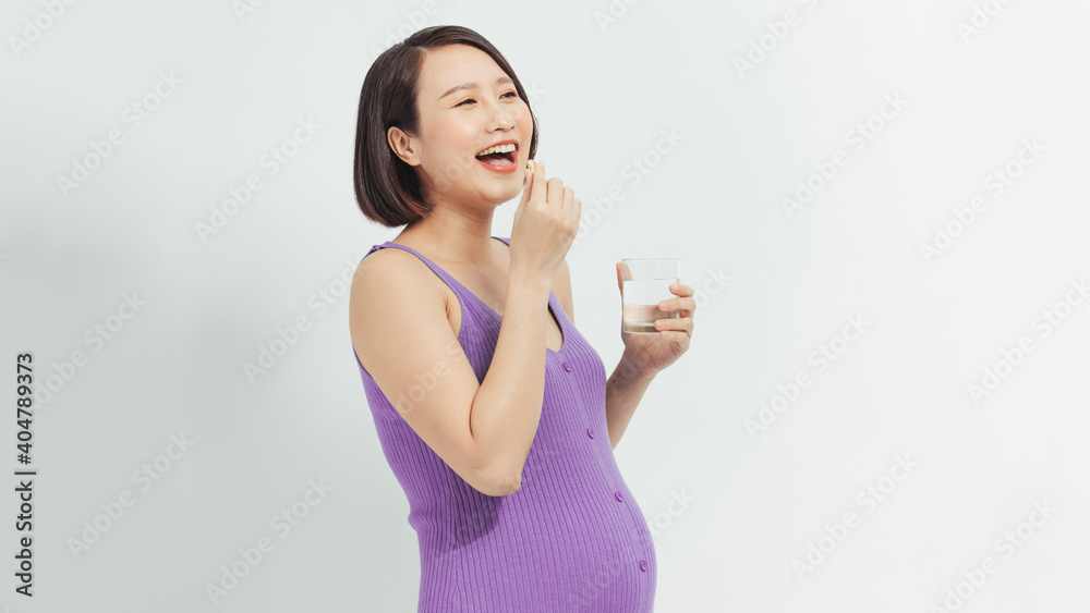 Pregnant woman holds vitamin's pill and glass of water Pregnant woman holds vitamin's pill and glass of water