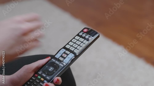 Une femme avec du vernis à ongle rouge utilise une télécommande.