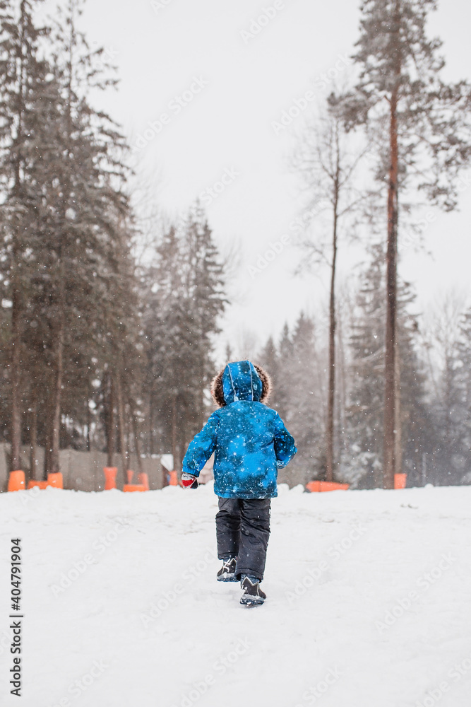 Little boy happily runs in the snow in the forest - play and walk in the fresh air - motion action blur Little boy happily runs in the snow in the forest - play and walk in the fresh air - motion action blur
