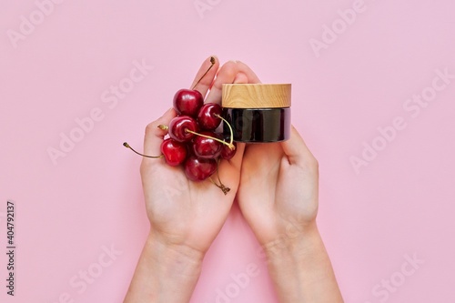 Natural healthy organic cosmetics, woman's hands, fruits, cherries, bottle with cosmetic product