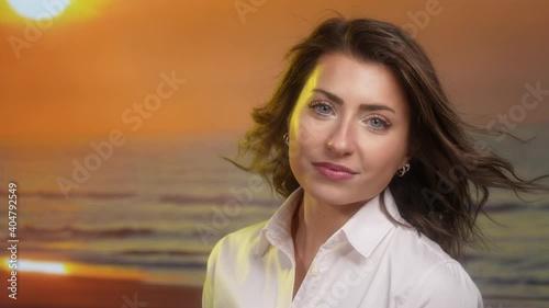 Attractice Caucasian woman on beach at sunset with hair blowing in the wind in slow motion close up photo