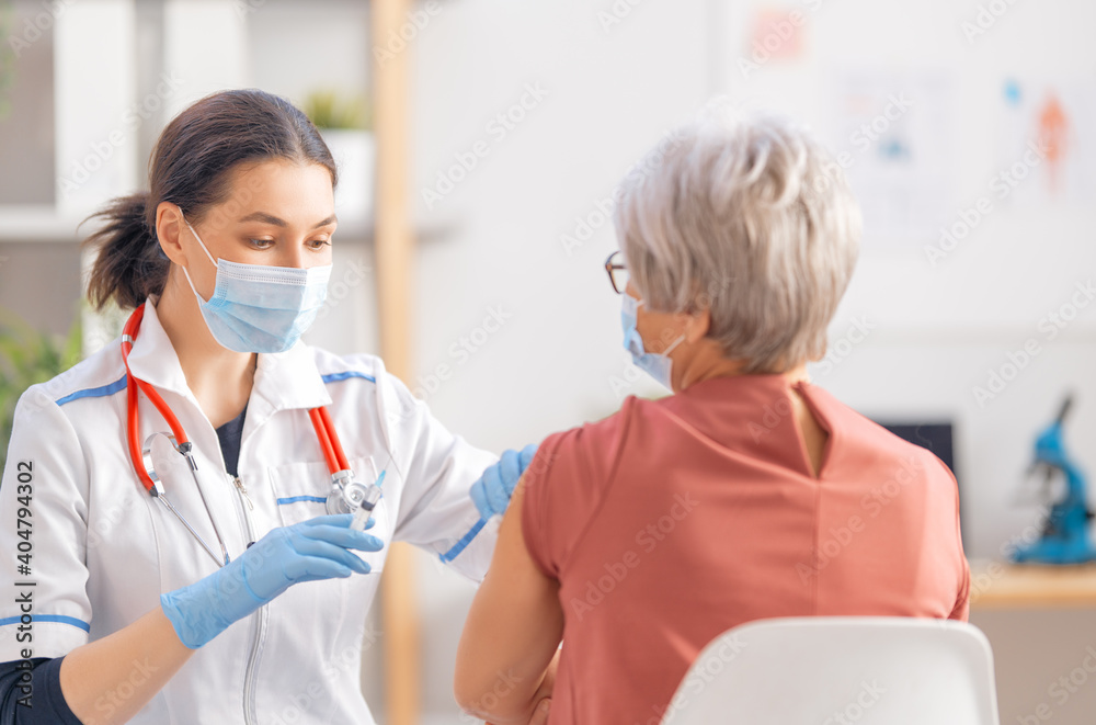 Doctor giving a senior woman a vaccination - obrazy, fototapety, plakaty 