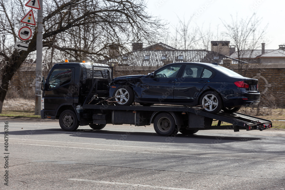 Private towing vehicle for emergency vehicle movement. Passenger car after an accident on a forklift truck on the road in motion