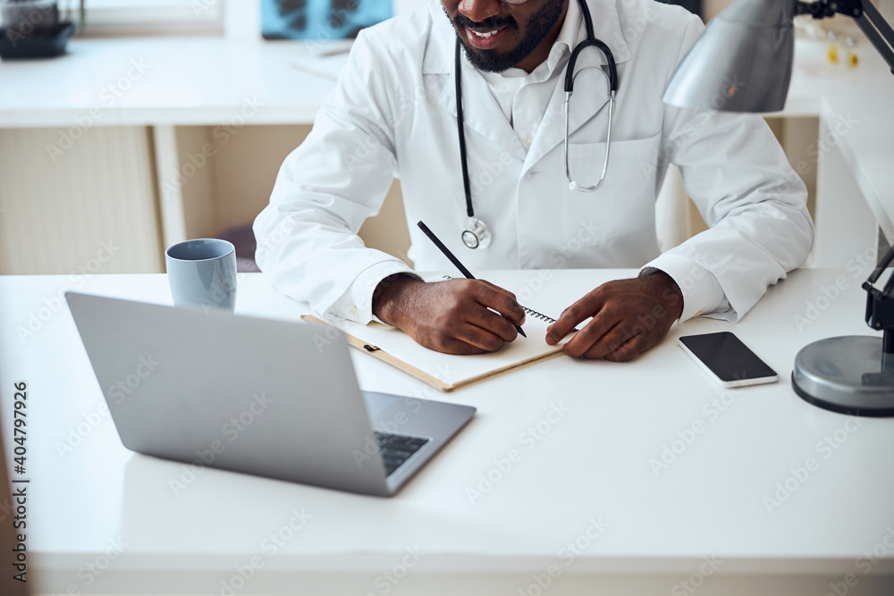 Multiethnic doctor copying the data from laptop screen Multiethnic doctor copying the data from laptop screen