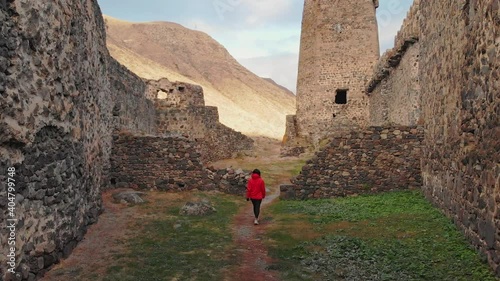 Female tourist walks down the path surrounded by Khertvisi fortress wall ruins. Cinematic filter and travel concept photo