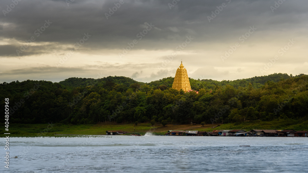 Φωτογραφία The scenery of the golden Phuthakaya pagoda shining in the sunset time at Sangkhlaburi, Kanchanaburi, Thailand