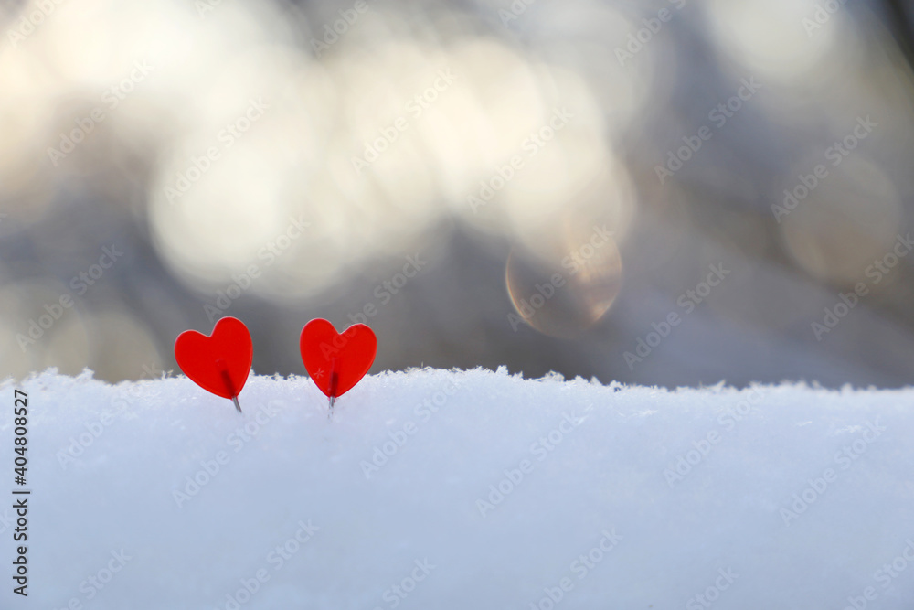 Fototapeta premium Two love hearts on the snow in sunlight. Background for romantic greeting card, Valentine's day