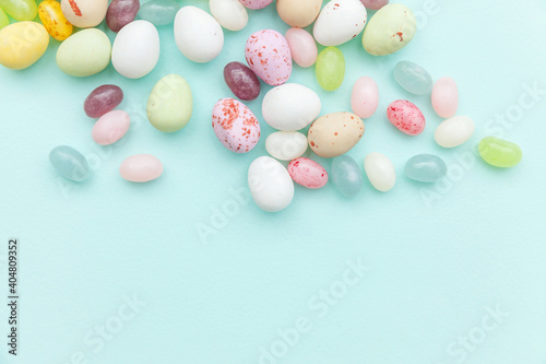 Happy Easter concept. Preparation for holiday. Easter candy chocolate eggs and jellybean sweets isolated on trendy pastel blue background. Simple minimalism flat lay top view copy space.