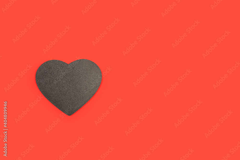 Corazón negro de pizarra sobre un fondo rojo liso y aislado. Vista superior. Copy space