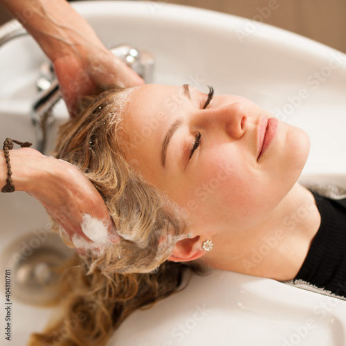 Hair stylist at work - hairdresser washing hair to the customer before doing hairstyle in a professional salon