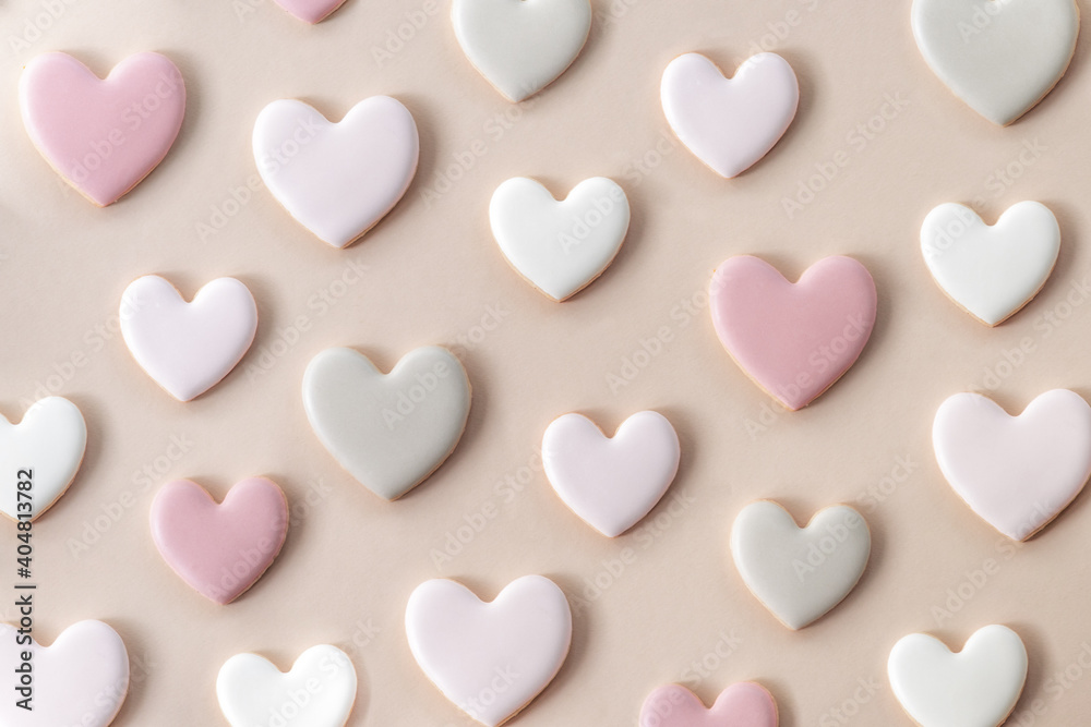 Heart-shaped cookies covered with sugar glaze in pastel colors (pink, gray, white) on a paper cream color background. Layout top view, close-up. Sweet composition for Valentine's Day. Heart-shaped cookies covered with sugar glaze in pastel colors (pink, gray, white) on a paper cream color background. Layout top view, close-up. Sweet composition for Valentine's Day.