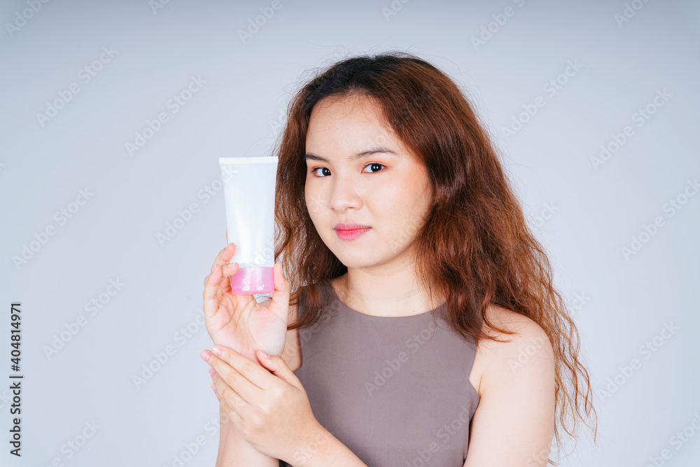 Asian curly hairstyle woman holding skincare cream lotion bottle isolate on white background. Asian curly hairstyle woman holding skincare cream lotion bottle isolate on white background.