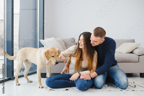 Young couple with a dog at home. Young man and a woman playing at home with dog.