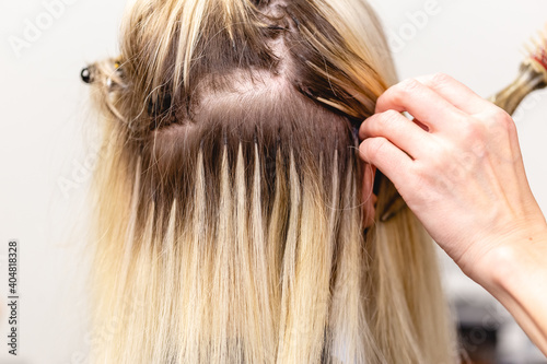Blonde hair extensions procedure in beauty salon