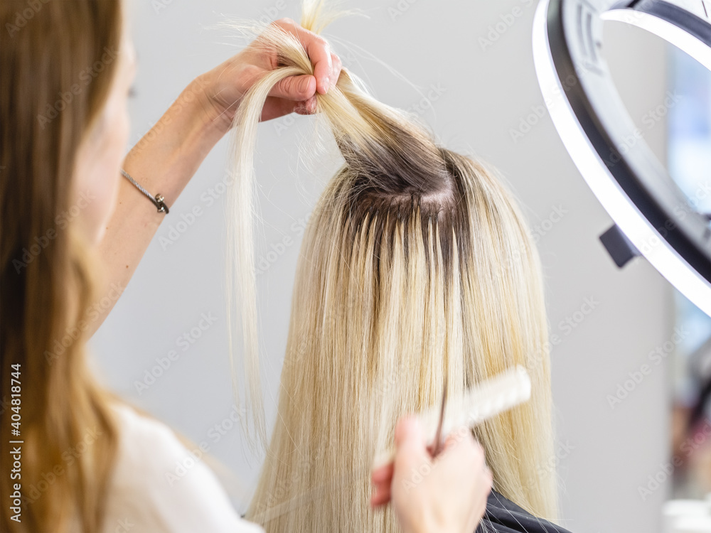 Fototapeta premium Blonde hair extensions procedure in beauty salon