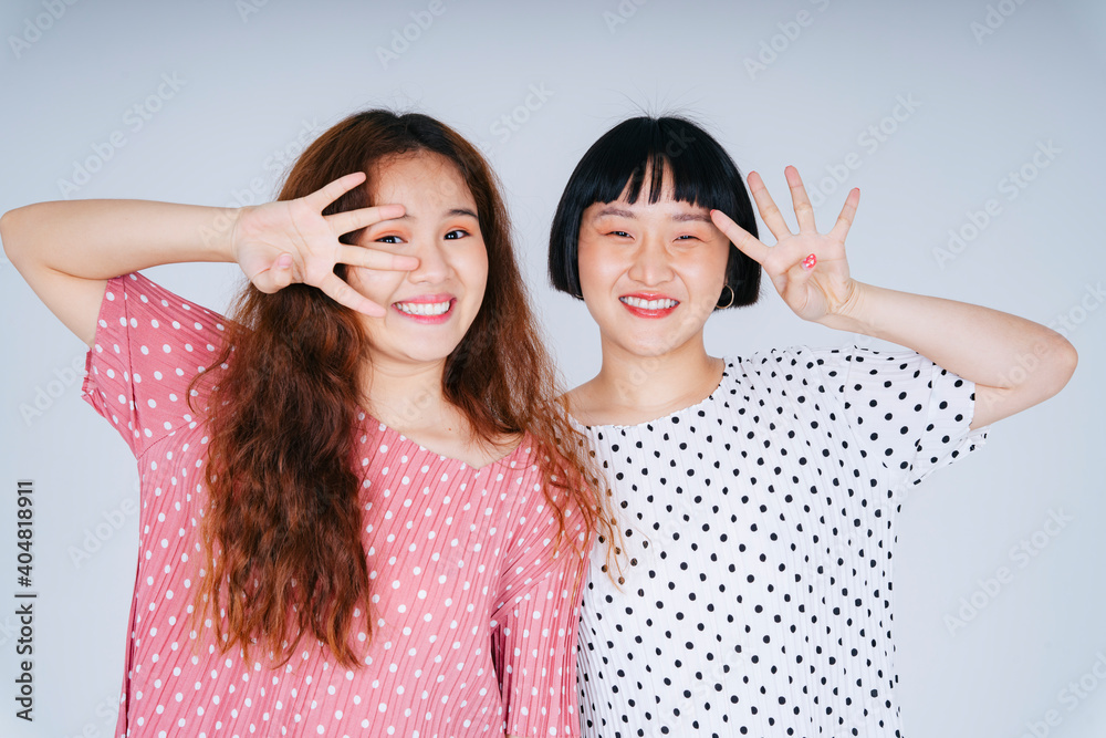 Two young asian women wearing dress expressing surprise and excited on white background. Two young asian women wearing dress expressing surprise and excited on white background.