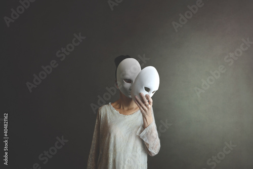 woman takes off the mask from her face but underneath her she has another mask, concept of hiding one's soul and oneself photo