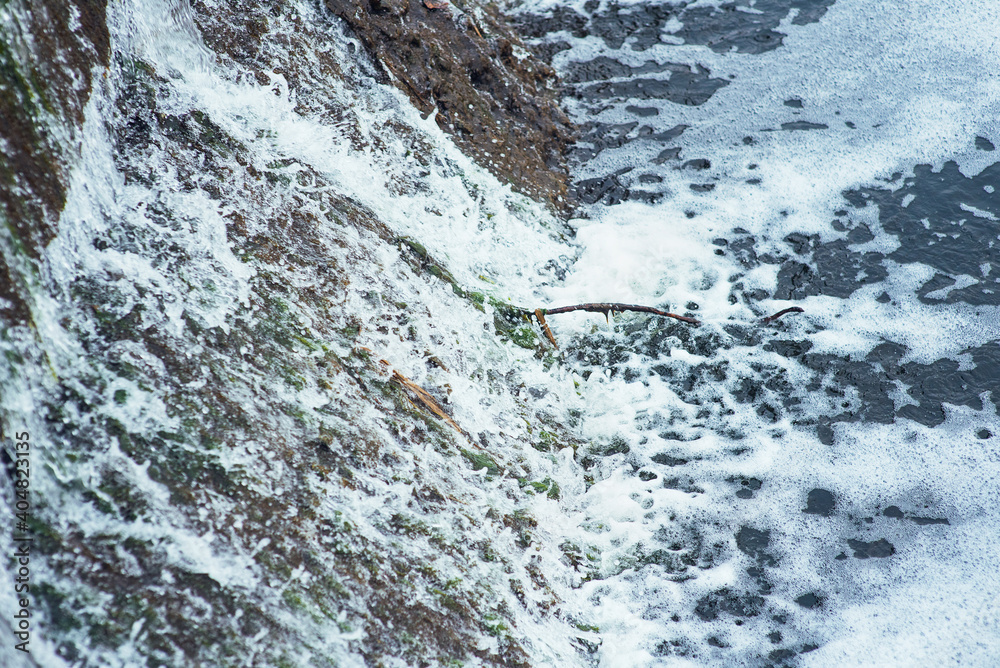 Fototapeta premium Water rapidly flows in a cascade along the concrete wall of the dam. Dam.