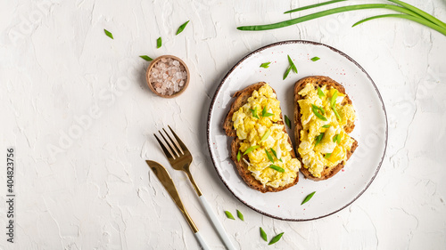 Scrambled eggs with green onion on wheat rye wholemeal crispy bread, homemade, healthy breakfast or brunch. Homemade meal, banner, menu recipe place for text, top view