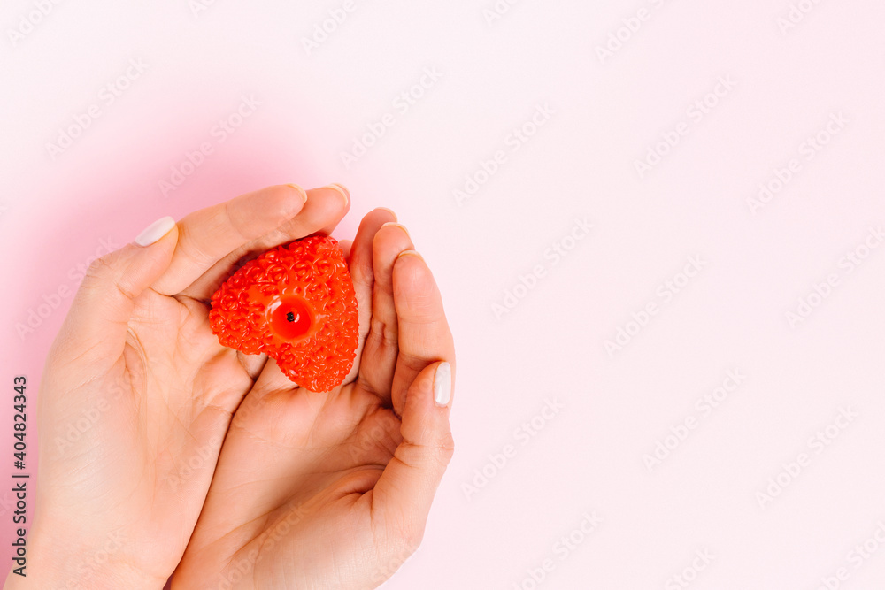 Hands hold a heart-shaped candle. Pink background and empty side space where your ad could be. Valentine's Day, charity. Hands hold a heart-shaped candle. Pink background and empty side space where your ad could be. Valentine's Day, charity.