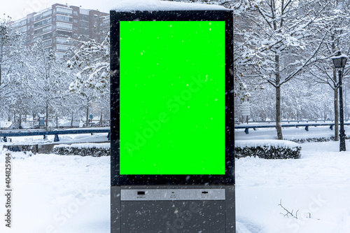 Vertical mock-up of city poster winter city with thick edges, green billboard in urban settings, empty street information placeholder on sidewalk with copy space for logo, advertising
