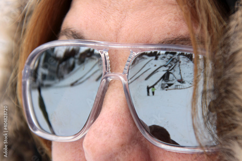Verspiegelte Sonnenbrille einer Frau spiegelt Skigebiet wieder photo