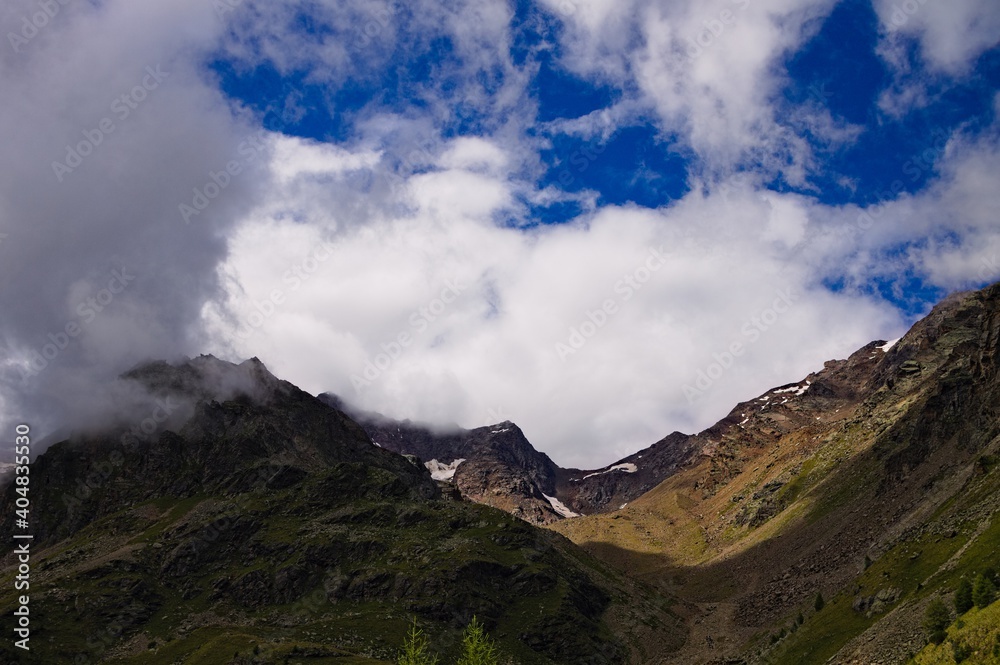 A mountain landscape with clouds in the sky on a summer day in the Italian Alps (Trentino, Italy, Europe) A mountain landscape with clouds in the sky on a summer day in the Italian Alps (Trentino, Italy, Europe)