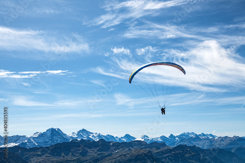 A tandem hang glider flying over the mountains.