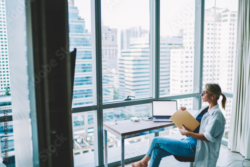 Pensive woman with laptop and documents in office