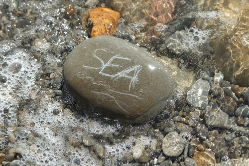 the stone on which the word sea is written. Top view of the sea summer wave and the sea white stones on the sand. Background, recreation, recreation