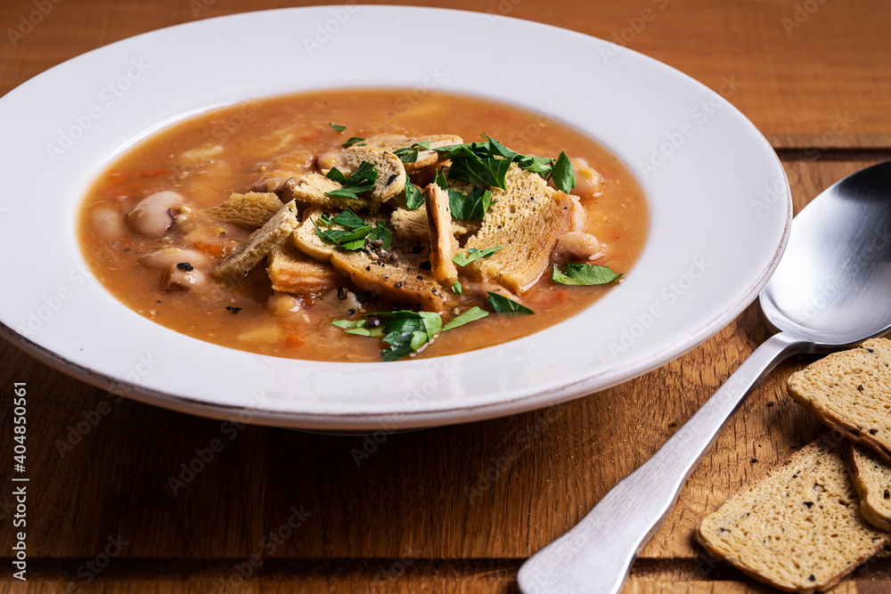 Bowl of tomato lentils soup with beans on wooden board Bowl of tomato lentils soup with beans on wooden board