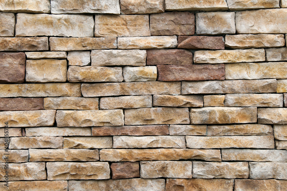 natural stack rock stone wall building facade with deep shadows in natural sunlight