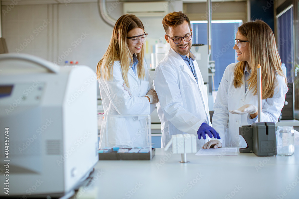 Researchers in protective workwear standing in the laboratory and analyzing liquid samples at ion chromatography equipment Researchers in protective workwear standing in the laboratory and analyzing liquid samples at ion chromatography equipment