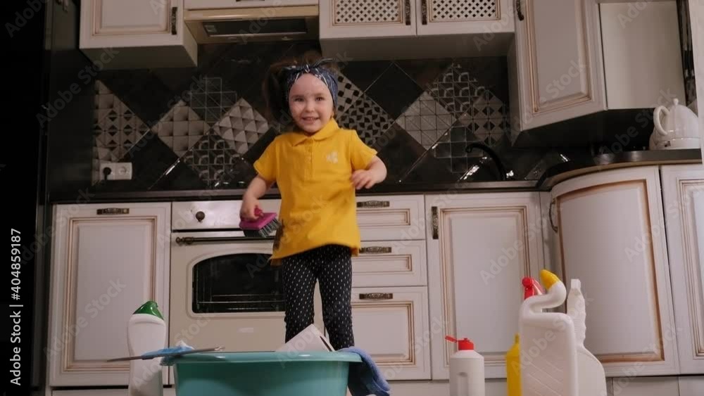 Portrait of a cute little girl with a handkerchief tied on her head at home on the floor among detergents. A little helper helps my mother clean the house. Portrait of a cute little girl with a handkerchief tied on her head at home on the floor among detergents. A little helper helps my mother clean the house.