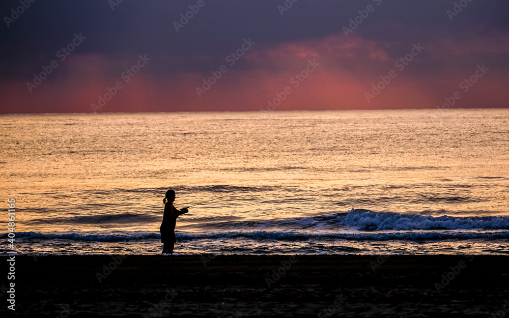 fishing in the sea with the sun in the background