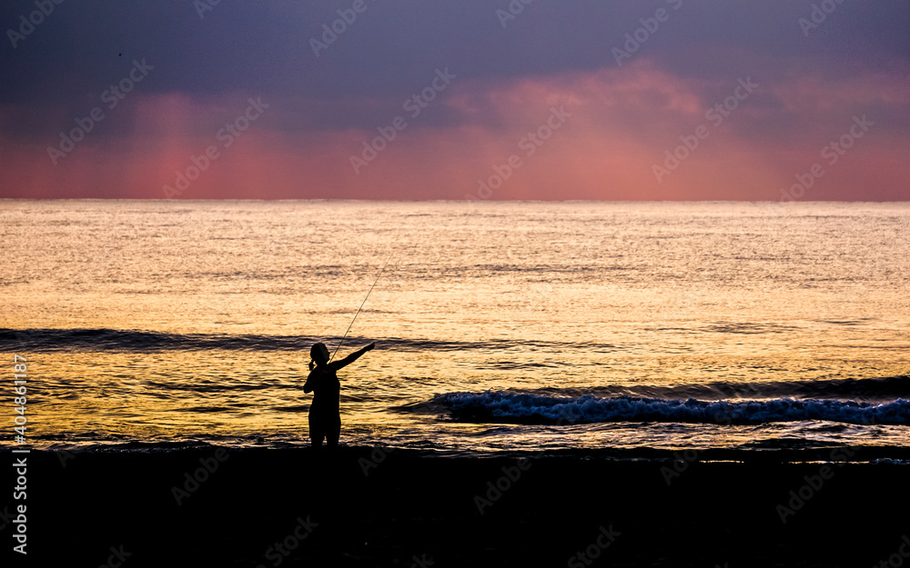 fishing in the sea with the sun in the background