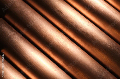 Copper pipes reflecting light, metal background, diagonal lines.