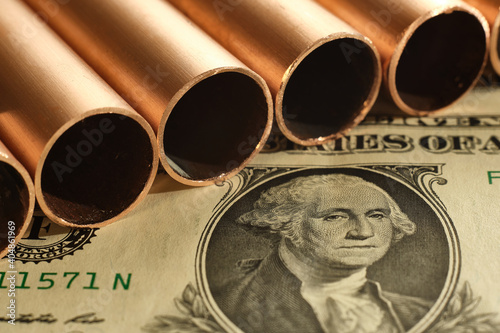 Close up of copper pipes and United States dollar. Commodity value and trading concept. photo