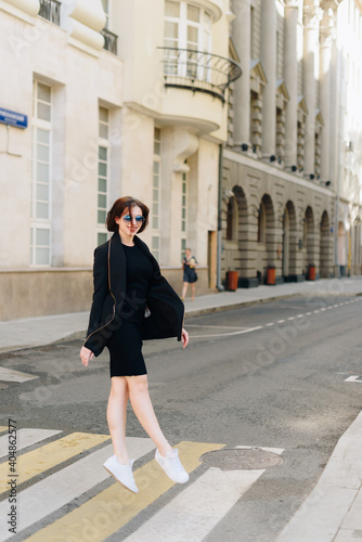 Beautiful woman in a black dress on a background of an urban landscape © ShevarevAlex