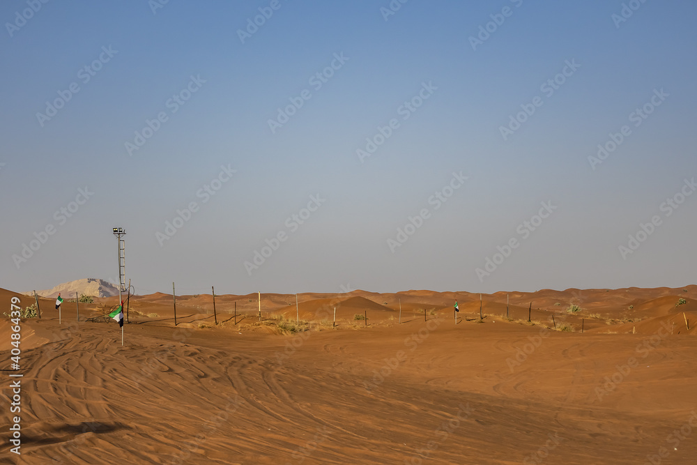 Obraz premium Desert dunes at Al Awir desert near Dubai with buggy vehicle at sunset light. Dubai, United Arab Emirates, Middle East.