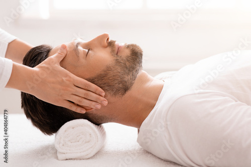 Female therapist making relaxing head massage for handsome man