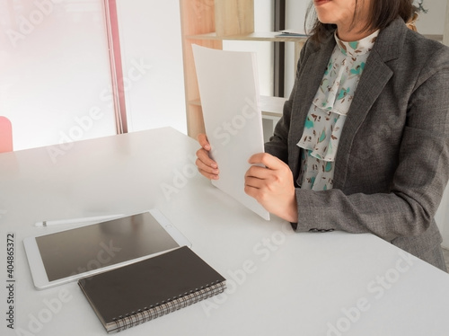 a business woman holding work sheets in to hand to share idea or plan to cowoker in a beautiful light office. taplate notebook on the bable, planing for business developing company and succeed in work photo