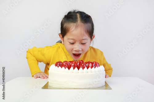 Little asian girl with strawberry cake. Kid with happy birthday cake on the table