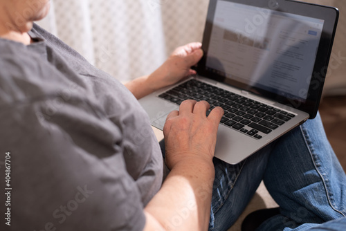 Old woman using a laptop, surfing the internet.