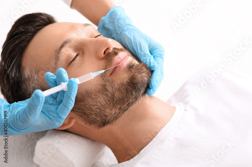 Closeup of bearded man getting nasolabial injection at clinic