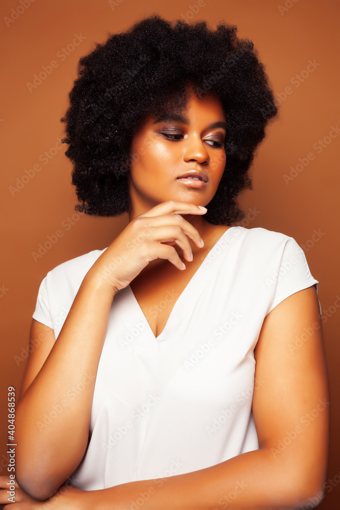pretty young african american woman with curly hair posing cheerful gesturing on brown background, lifestyle people concept pretty young african american woman with curly hair posing cheerful gesturing on brown background, lifestyle people concept
